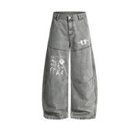 Washed grey Curved Blade denim jeans, baggy wide leg with a curved seam down each leg, white twin cherub archers on one thigh and a hand-lettered Faith Over Fear graphic on the other