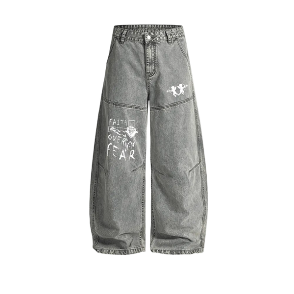 Washed grey Curved Blade denim jeans, baggy wide leg with a curved seam down each leg, white twin cherub archers on one thigh and a hand-lettered Faith Over Fear graphic on the other
