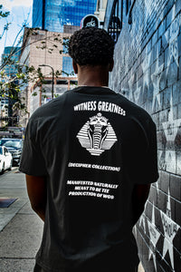 Back of the black Meant To Be Tee with the Decipher Collection pharaoh and cobra graphic, shot on a city street
